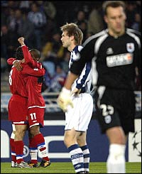Real Sociedad players stand dejected whilst Lyon's Malouda and Juninho celebrate