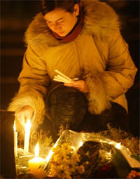 Woman lights candles in front of the parliament building during an all-night vigil.
