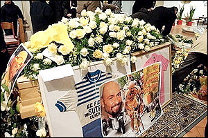 Pictures and shirts from the career of Pantani celebrating his Tour de France and Giro d'Italia successes surround his coffin