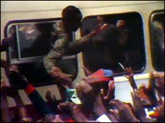 Soldier leans out of bus to shake hands with supporters
