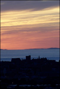 The sun setting against the Aberystwyth Town coastline (Adam Holt)
