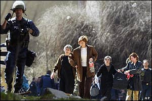 UN police officer guards Serbian family as they evacuate their home in Mitrovica