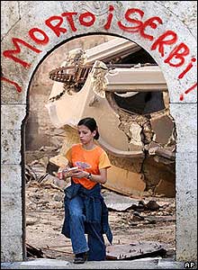 Young ethnic Albanian girl walks under monastery hallway with slogan 