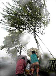 Three pedestrians in Hangzhou struggle with their umbrellas in strong winds and rain brought by the Typhoon Rananim on Thursday August 12, 2004 (Xinhua Photo) 