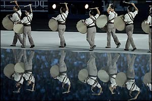 Drummers' shadows reflect in the lake