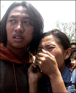 A man comforts a woman as they wait for news about a relative who works at the embassy.