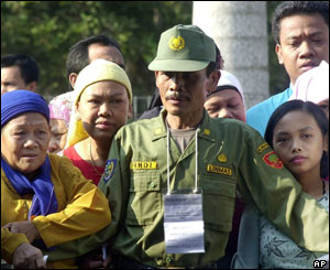 A security officer stands guard as voters wait for their turn in presidential elections at a polling station in Cibubur, south of Jakarta, Sept 20, 2004.