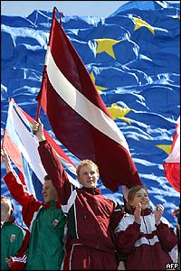 Latvians hold their flag in front of the EU's flag during the EU enlargement ceremony in Brussels