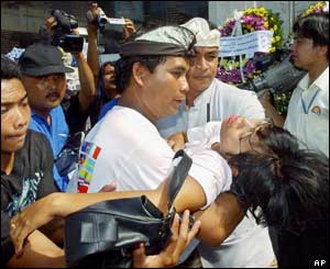 A woman overcome with grief is carried from the Bali bombing memorial site 