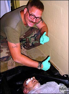 Specialist Charles Graner smiles over the body of a dead Iraqi.
