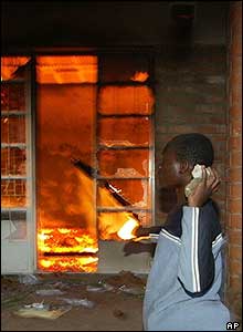Opposition supporter throws a brick through the burning windows of the UDF office in Ndirande, near Blantyre