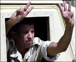 Saudi policeman makes a victory sign as he leaves the Oasis compound, 30 May 2004