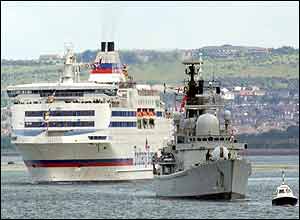 The British Royal Navy warship HMS Gloucester escorts a ferry from Portsmouth Harbour