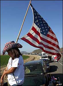 A girl with a US flag waits for the motorcade carrying Reagan's casket