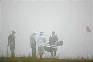Jim Furyk and Ben Curtis wait in the fog on the 11th green