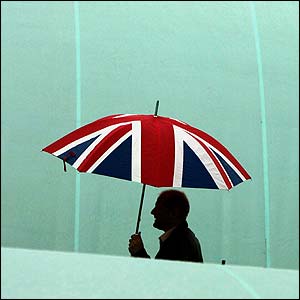 A tennis fan takes cover as the rain continues to fall