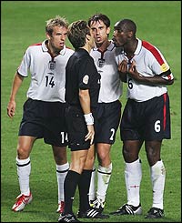 Phil Neville, Gary Neville and Sol Campbell argue with referee Urs Meier