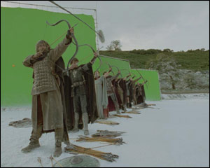 Actors stand in a field firing arrows - but what are those green screens?