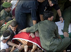 Palestinians clamber onto the coffin as it passes through the crowd