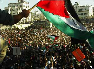 A Palestinian flag is waved above a crowd of people in Ramallah