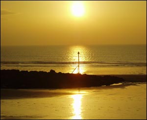 The sun setting over the sea defences at Dinas Dinlle, near Caernarfon, north Wales (Mike Taylor)
