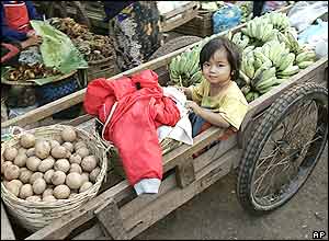 A young Lao girl takes a ride in a vegetable cart in one of Vientiane's many morning markets Thursday, Nov. 25, 2004. Vientiane,