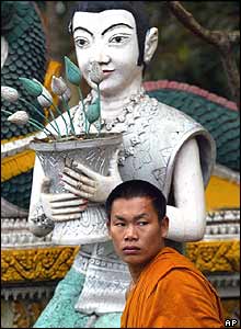 A Laotian Buddhist monk watches people pray at Srimuang pagoda in Vientiane, Laos, Friday, Nov. 26, 2004.