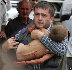 A man carries an injured child who escaped from a seized school in Beslan