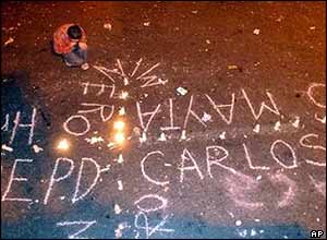A boy prays on his knees in front of a cross of candles in La Paz