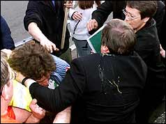 Back of Prescott with egg splattered on jacekt and left arm around protester