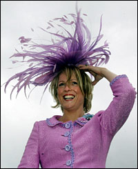 A racegoer holds onto her hat