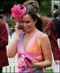 A woman chats on her mobile phone between races