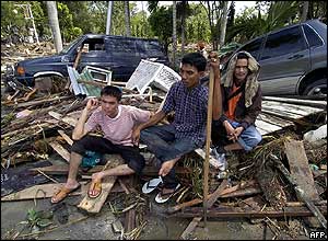Residents of Banda Aceh sit as they wait for help following a devastating quake and series of tidal waves that struck the province