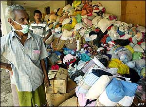 An aid worker stands beside piles of clothes to be distributed to tsunami victims in the south-western Sri Lankan town of Galle