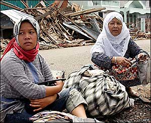 Women sit amid some belongings they managed to recover in Meulaboh, west Aceh, 30 December 2004