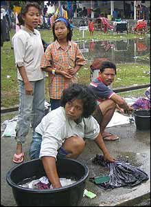 Woman washes clothes in makeshift refugee centre