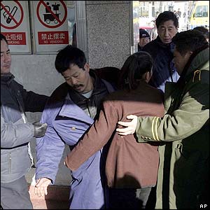 A couple is pushed by plain clothes police as they try to mourn Zhao Ziyang