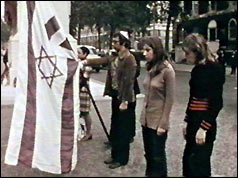 Three protesters hold Israeli flag