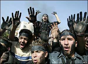 Hariri supporters with their hands stained black from burning tyres shout anti-Syrian slogans in Sidon