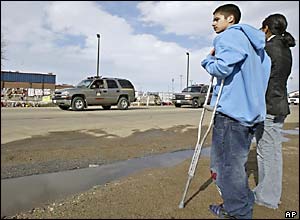 Shooting survivor Cody Thunder, left, and his girlfriend watch the funeral procession pass the school