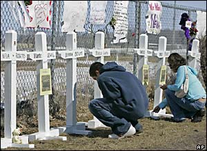 Chongai'la Morris, left, and Alex Roy place ritual tobacco at a makeshift memorial outside the Red Lake High School