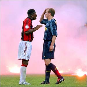 AC Milan's Clarence Seedorf and Inter Milan's Estaban Cambiasso chat as smoke billows at the San Siro