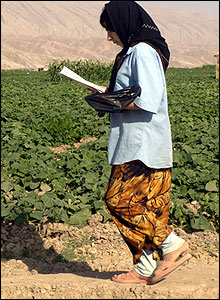 Young girl reads schoolwork while walking by fields of crops