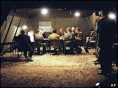 Military leaders seated round table in tent at night