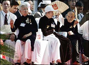 Elderly women spectators use fans to keep cool 