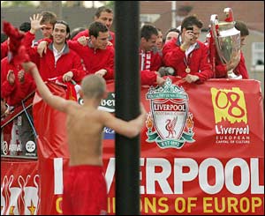 A fan watches the Liverpool parade from a lamp post