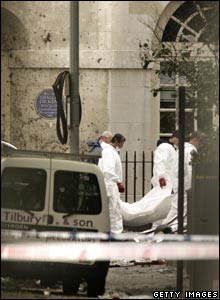 Police forensic officers remove a body from the scene of a bus bombing 
