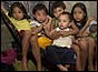 Child refugees sitting in hammock after typhoon in 2004