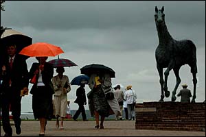 Racegoers shelter from the rain at Goodwood