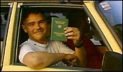 An East German holds up his new West German passport as he crosses border